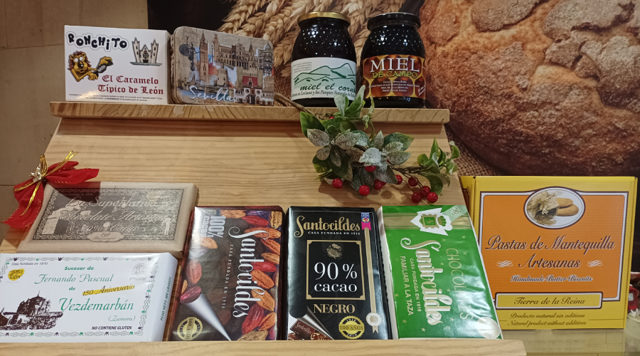 tabletas de chocolate, pastas y miel en un mostrador de madera en Horno de León